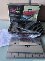 Box, grill body, grate, accessories visible