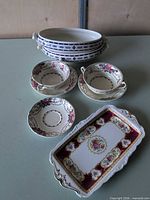 All items in lot: three blue-border oval bowls, two floral teacups, two saucers, burgundy floral tray