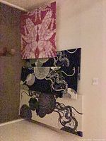 Three canvases leaning against wall showing colour variations and abstract designs