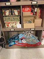 Shelved lot showing star tree topper, blue sequin ornaments, red garland, storage boxes