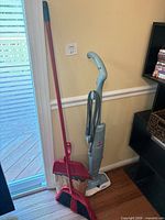 Steam mop, broom, and dustpan standing upright