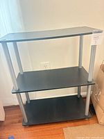 Full view of 3-tier black TV stand with silver legs