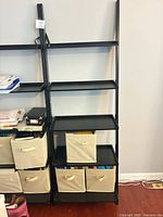 Front view of black ladder shelf with fabric bins and books for scale