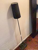 Full view of black metal floor lamp against wall