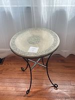 Full view of round table showing embossed metal top and wrought iron base