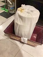 Rectangular brown and gold metal planter with lot tag 102, bag inside
