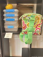 Front view of floral lunch bag, stack of four Sistema containers, kraft paper bag and yellow egg container