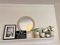 Overall mantel view showing print, sign, mirror, four planters