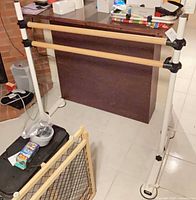 Overall view of freestanding double rail ballet barre showing wood bars and white metal frame