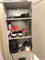 Interior shelves of gray cabinet showing toiletries, grooming tools and candle