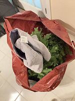 Top view of red storage bag containing artificial tree branches and grey quilted cover