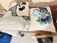 Comforter folded beside floral pillow on table