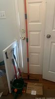 Lot overview showing rake, broom, spreader, boxed trimmer