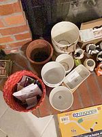 Top view of assorted planters including red basket, white plastic pots, terracotta pot and rectangular beige planter