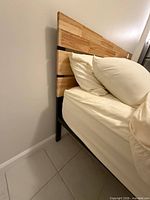 Bed showing wood headboard side and black metal leg