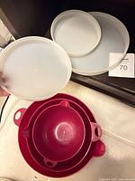Nested set of three red/pink mixing bowls and three white lids displayed