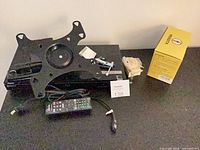 Full lot showing Blu-ray player, wall mount plate, remote, cable, hardware, yellow box