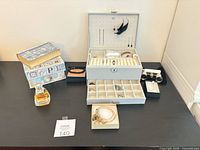 Overview of jewelry box open with contents, opera glasses, perfume bottle, decorative boxes