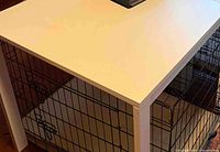 Corner and top surface of one white table, dog crate beneath