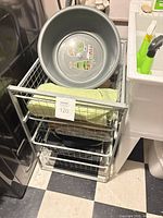 Wire storage cart with three baskets, basin and fabric items visible