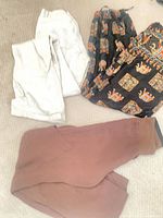 Three pairs of trousers laid out: off-white, black elephant print, brown jogger