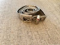 Rolled metal belt showing buckle stamped ARMANI and mesh strap