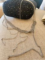 Full view of the silver multi-strand necklace draped on couch