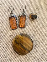 Group shot showing amber earrings, tiger’s eye heart pendant, and tiger’s eye palm stone