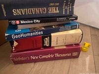 Stacked books showing spines: The Canadians, Mexico City travel guide, GeoHumanities, Roget's Thesaurus, Webster's Thesaurus