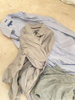 Striped blue-white Tommy Hilfiger shirt, beige shirt and grey sweater on floor