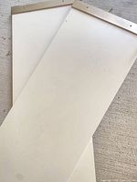 Pair of white shelves showing top surfaces and metal end caps