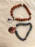 Both bracelets laid flat showing bead colours and silver charms