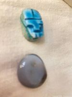 Blue carved scarab bead and grey agate cabochon on fabric