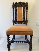 Full front view of carved oak chair showing upholstery and barley-twist legs