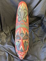 Full view of elongated carved wood mask showing overall paint and form