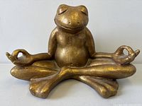 Front view of gold frog statue in lotus pose