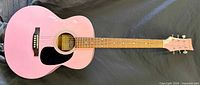 Front view of pink acoustic guitar showing full body, neck, and headstock