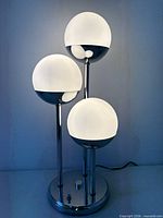 Full view of lit three-globe chrome lamp
