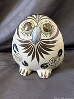 Front view of owl figurine showing eyes, beak, feather and spiral motifs
