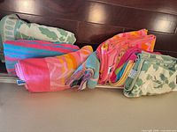 Stack of assorted striped and floral beach towels folded on shelf