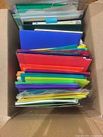 Box filled with stacked colorful plastic folders and binders