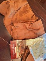 Folded burnt orange damask tablecloth and napkins with Autumn Harvest packaging card visible