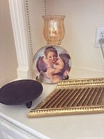 Group view showing amber hurricane, cherub plate on stand, gold tray, black trivet