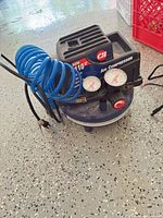 Full view of Campbell Hausfeld pancake compressor with hose and power cord