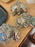 Three ornate silverplate flatware caddies on table