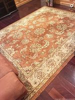 Full view of rug showing rust field, cream border, floral motifs