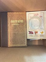 Character Sketches hardcover beside Simple Home Remedies pamphlet and plastic bowl in box