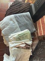 Lot overview showing brown knit throw, grey fringe throw, stack of folded white and mint linens