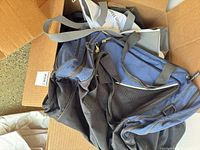 Box containing blue and black backpack with other bags visible