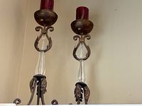 Two matching metal and glass candlestick holders with red pillar candles displayed side by side